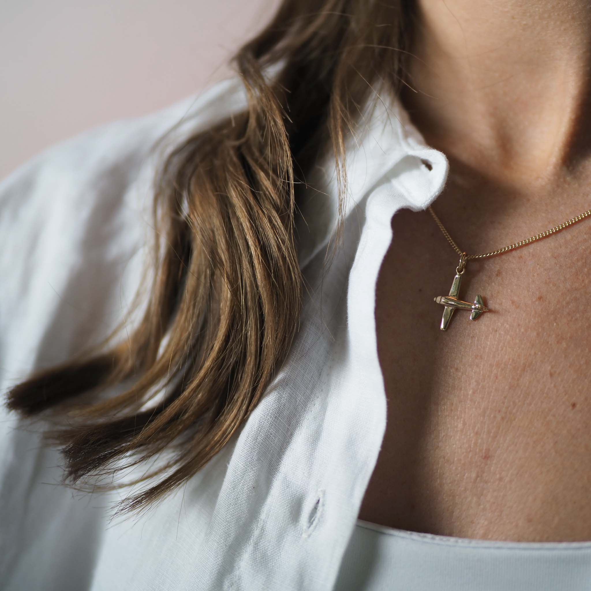 9ct gold airplane charm necklace. A polished solid gold pendant symbolising travel and freedom. Available in yellow, rose, or white gold.