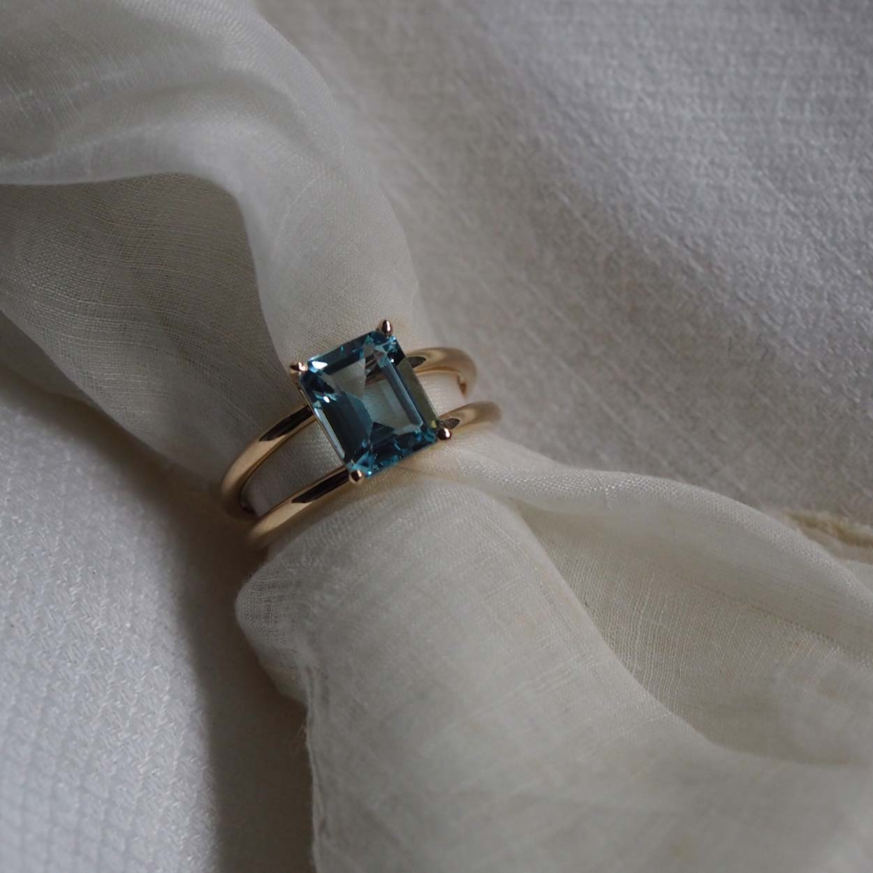 Bridal Emerald-Cut Aquamarine Ring by Bianca Jones Jewellery, London: Joyful aquamarine set on two handcrafted yellow gold bands.