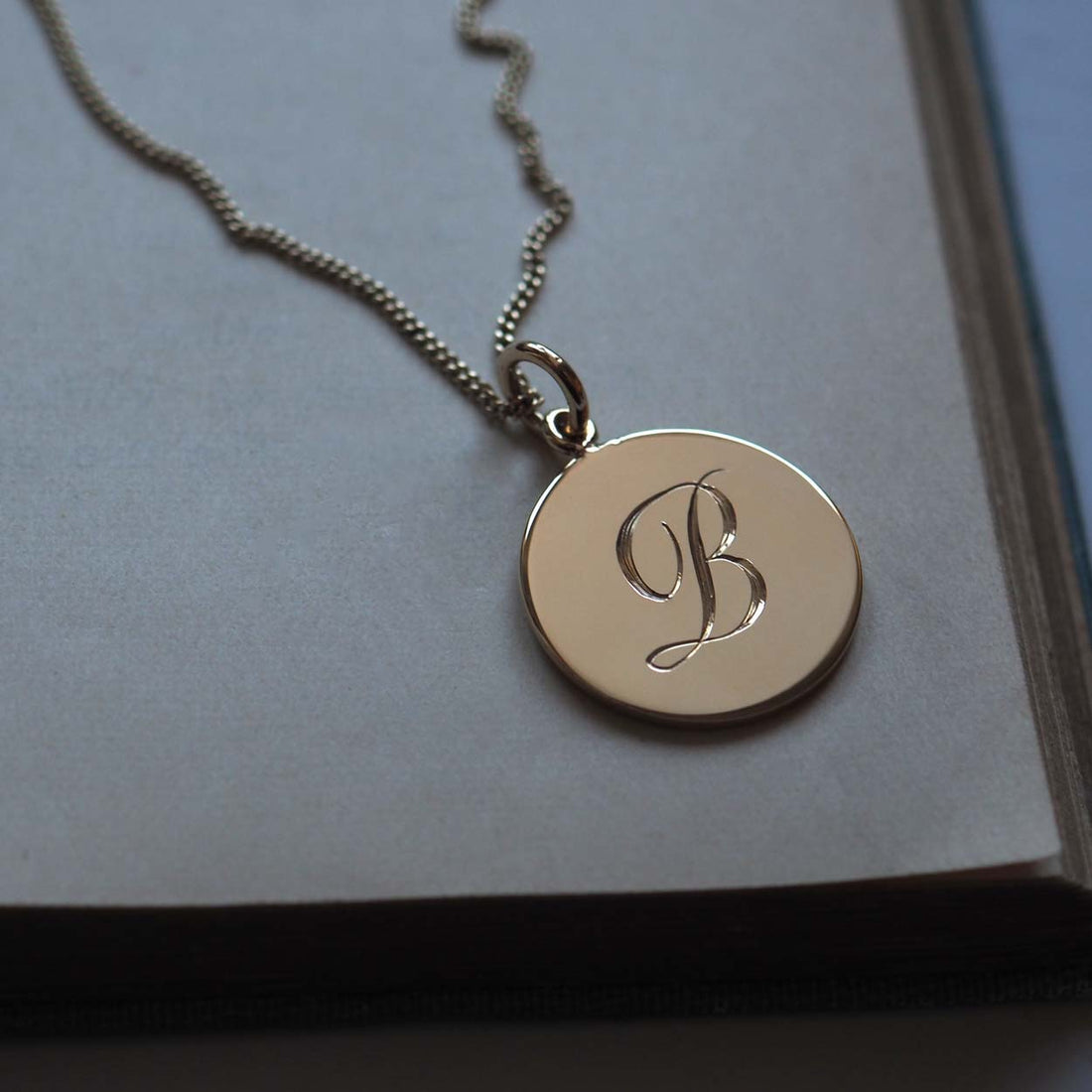 Bianca Jones handcrafted and hand-engraved solid 9ct gold initial charm, available in rose, white, or yellow gold, showcasing bespoke craftsmanship.