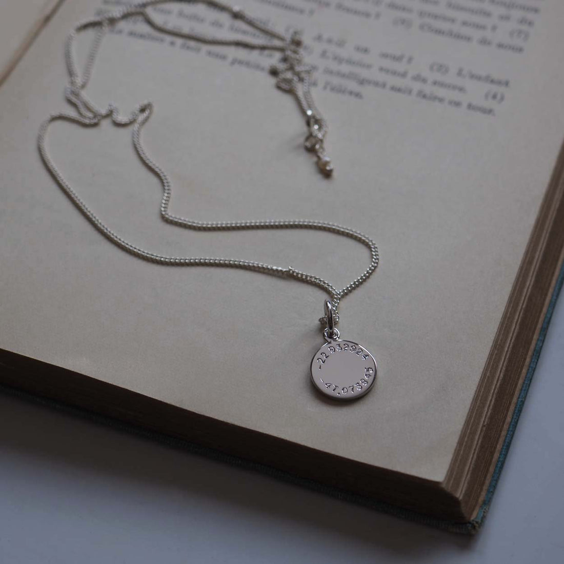 Latitude and Longitude Mini Necklace charm in solid 9ct gold, hand-engraved with coordinates. A timeless keepsake symbolizing cherished memories.