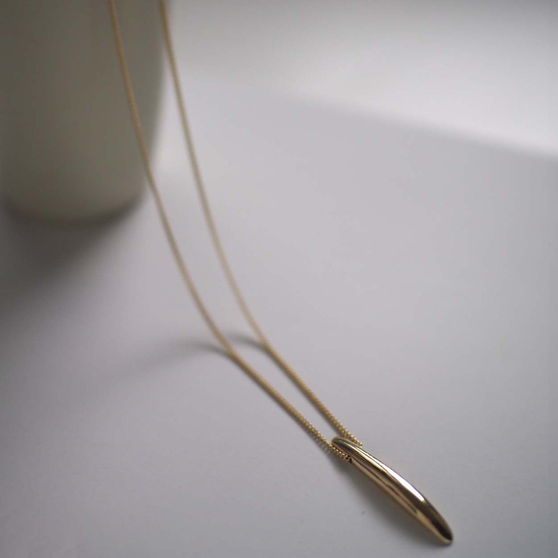 Sculptural solid gold bar necklace with a curved Brancusi-inspired form – Forever Strong Necklace, handmade in London.