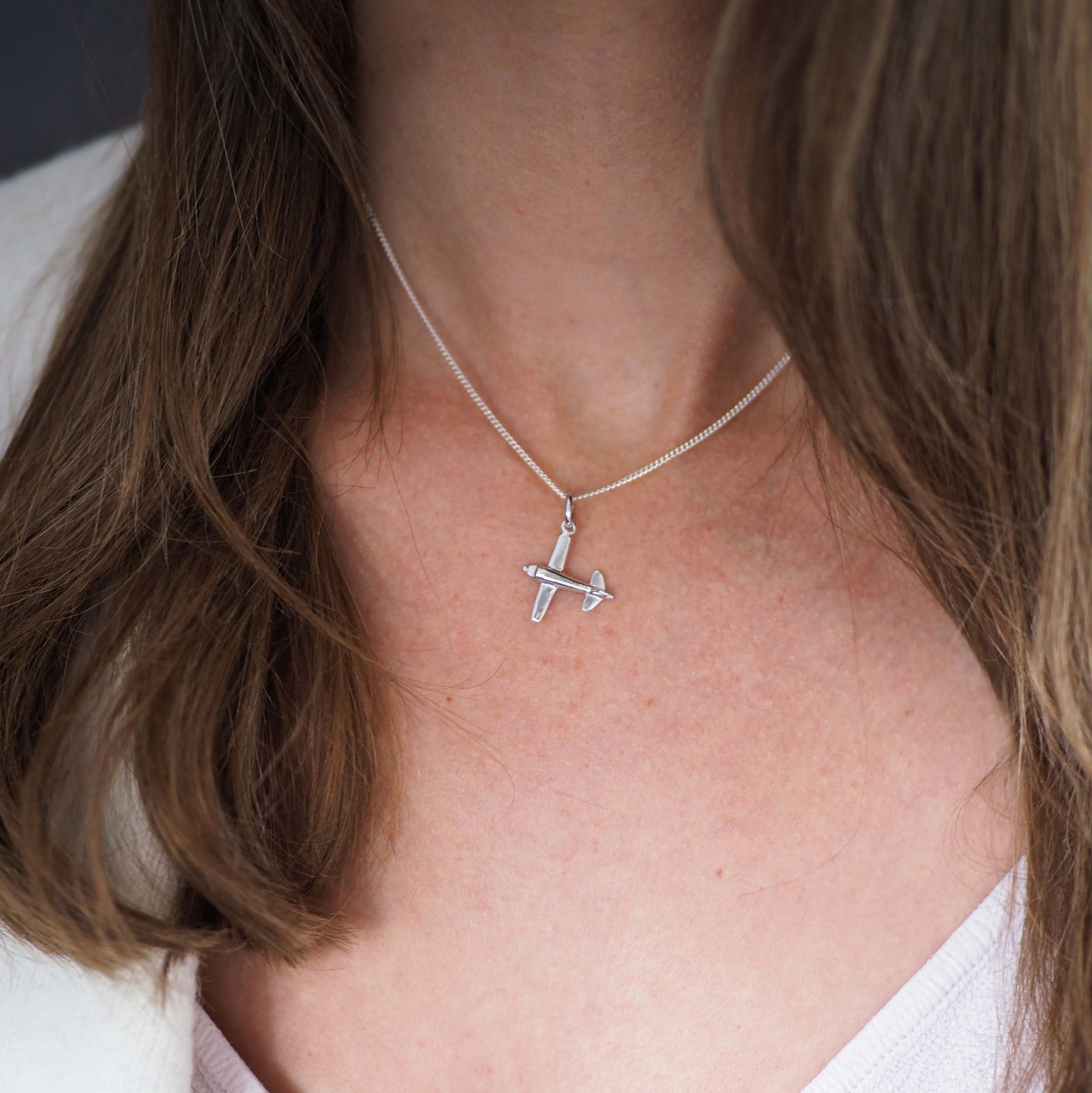 Model wearing sterling silver aeroplane necklace at collarbone