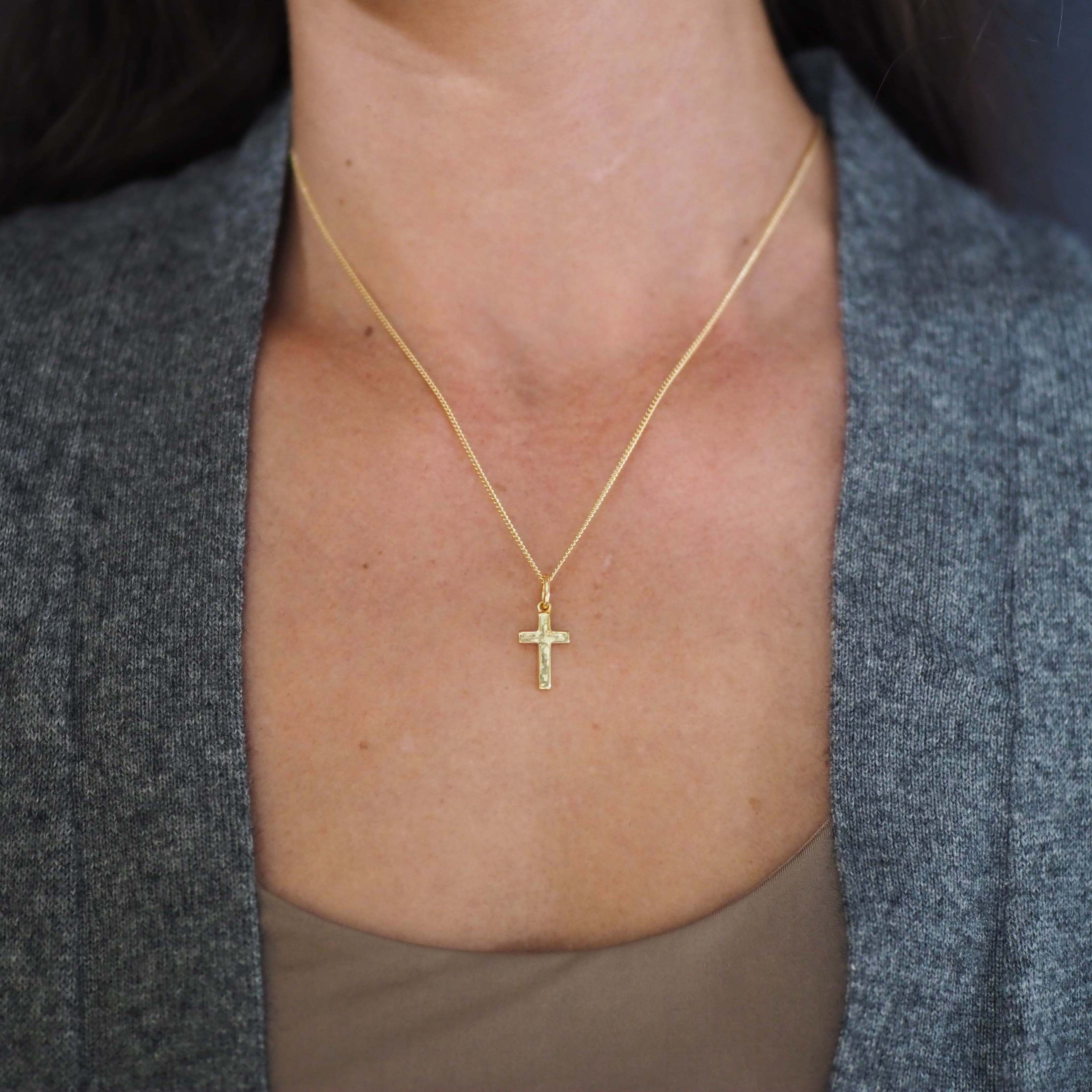 Woman wearing the Solid Gold Cross Necklace, showing soft proportions and detailed hand-texture