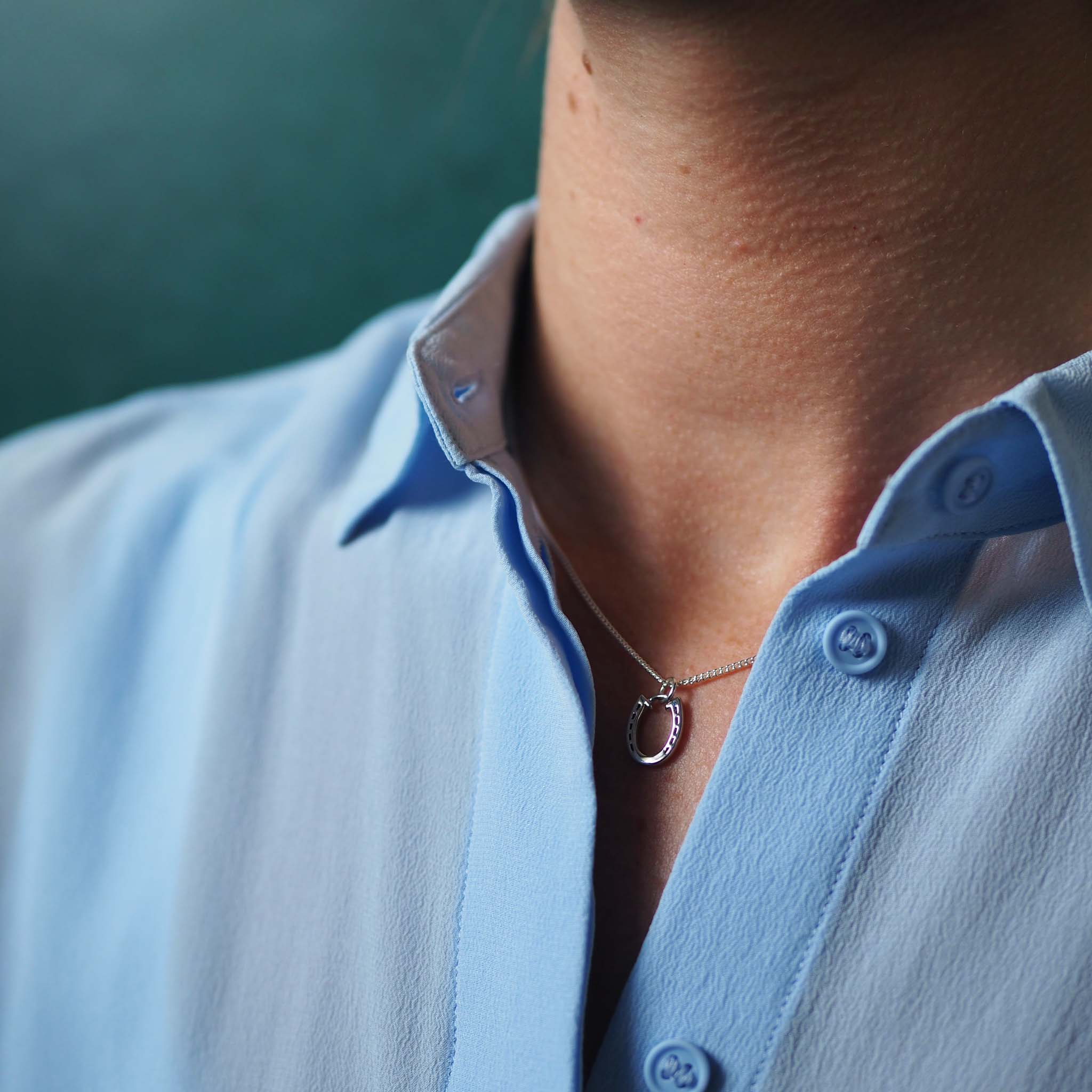 Woman wearing the Horseshoe Necklace sitting on their collar bone in solid gold, a talisman of luck and protection