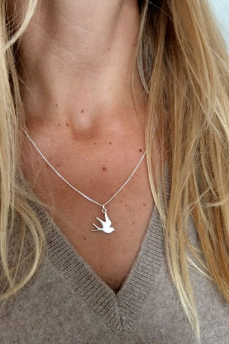 White gold swallow necklace on model – handcrafted talisman symbolising hope, love, and safe return