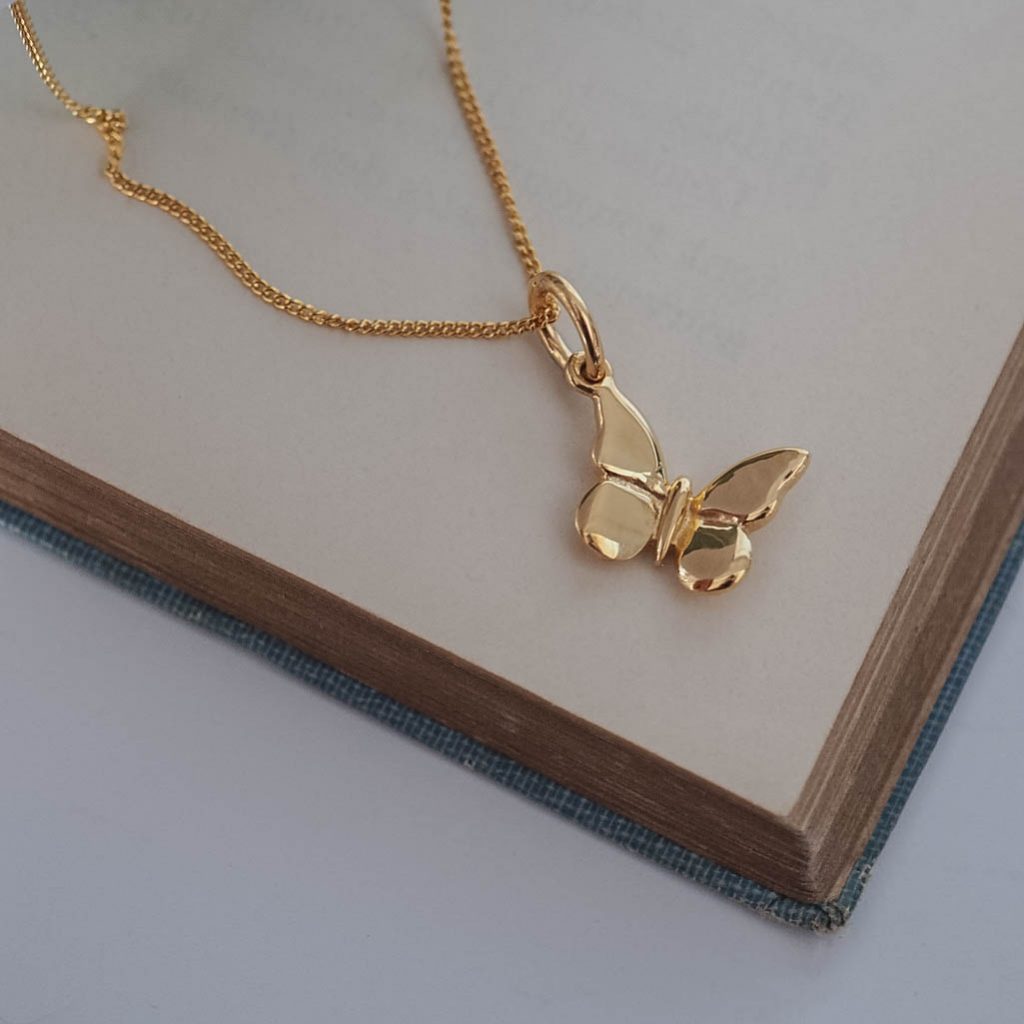 Delicate solid gold butterfly pendant, symbolising transformation and renewal, shown from the front