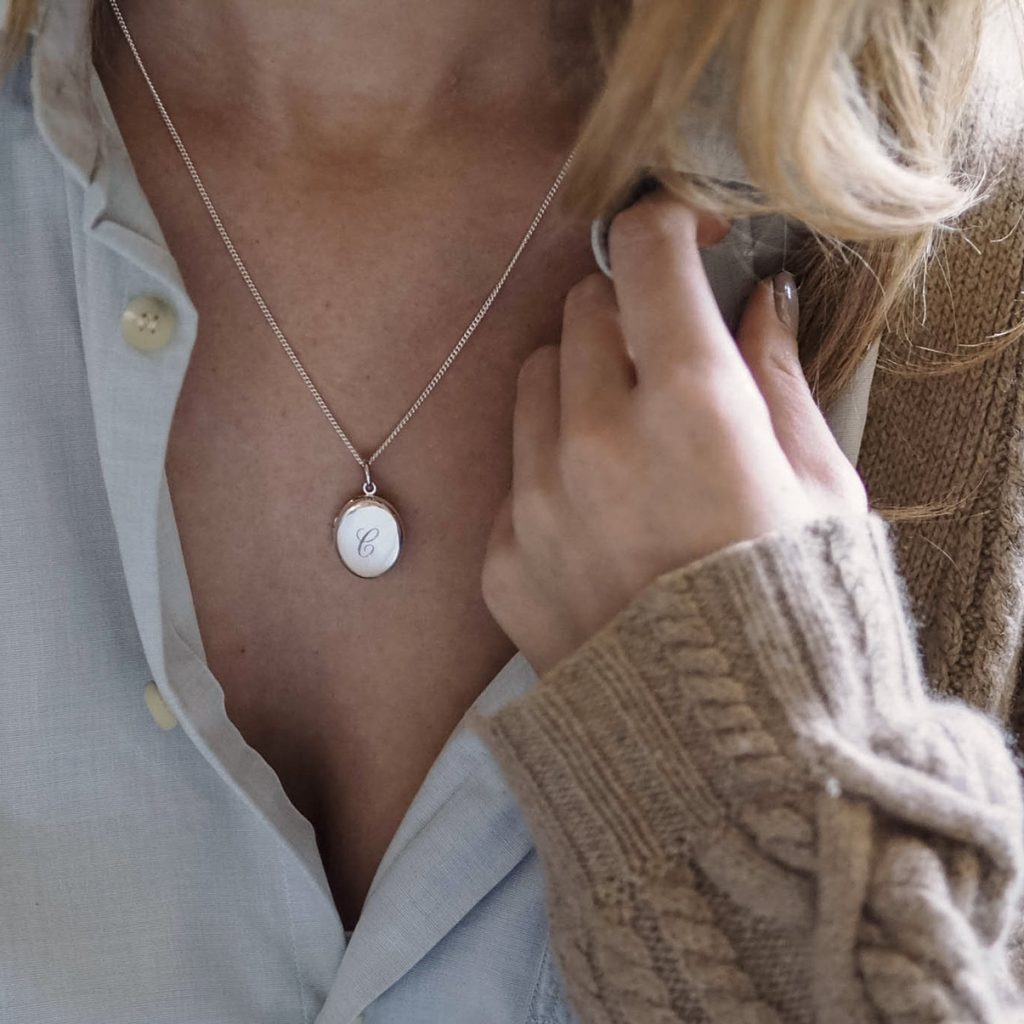 Sterling Silver Initial Locket Necklace with hand-engraved initial, designed to hold cherished mementoes like photographs or locks of hair. A timeless heirloom inspired by Victorian love tokens.
