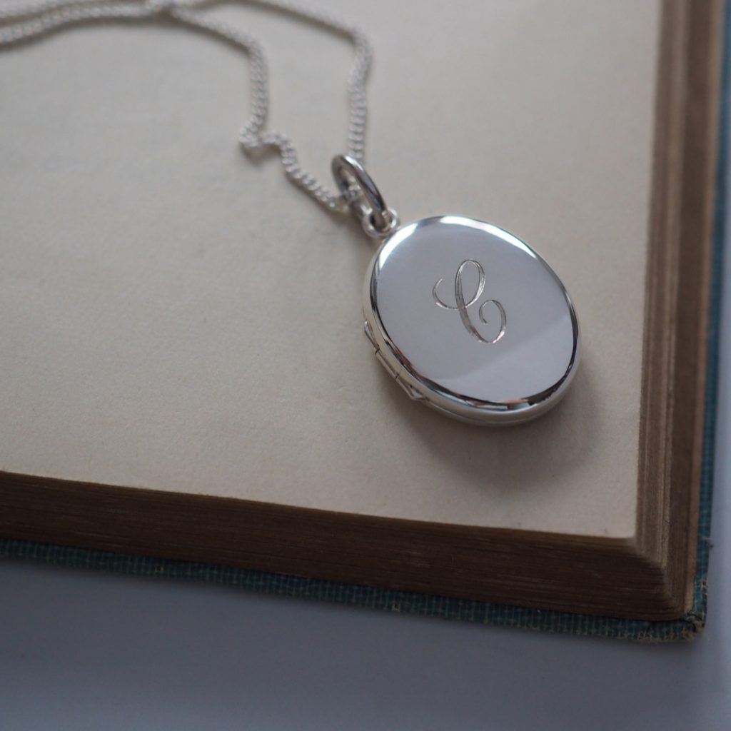 Sterling Silver Initial Locket Necklace with hand-engraved initial, designed to hold cherished mementoes like photographs or locks of hair. A timeless heirloom inspired by Victorian love tokens.
