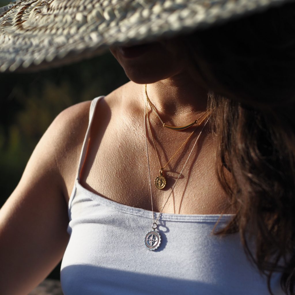 Two gold vermeil compass necklaces of varying lengths layered together.