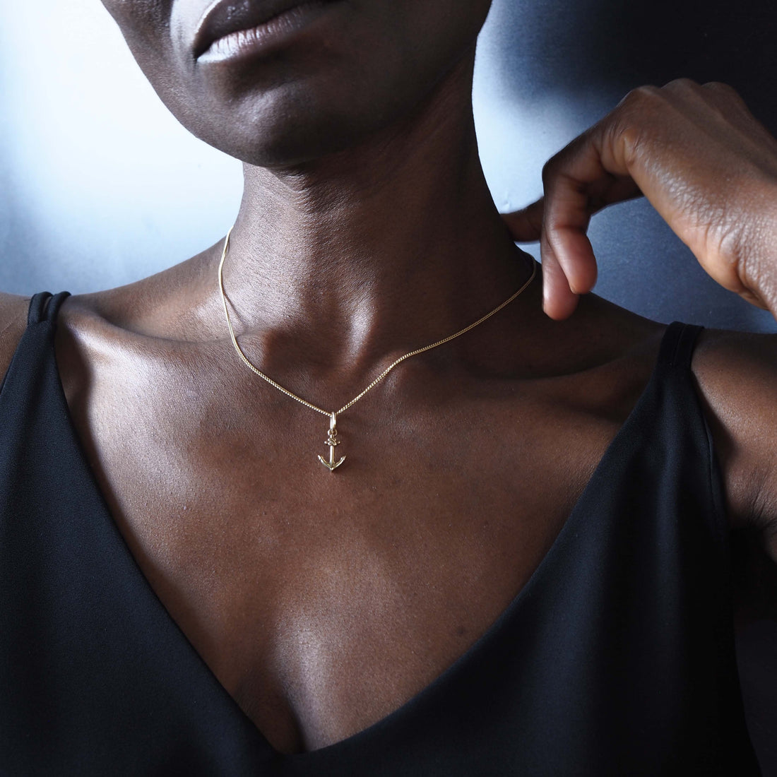 Woman wearing 18ct solid gold anchor necklace close to neckline