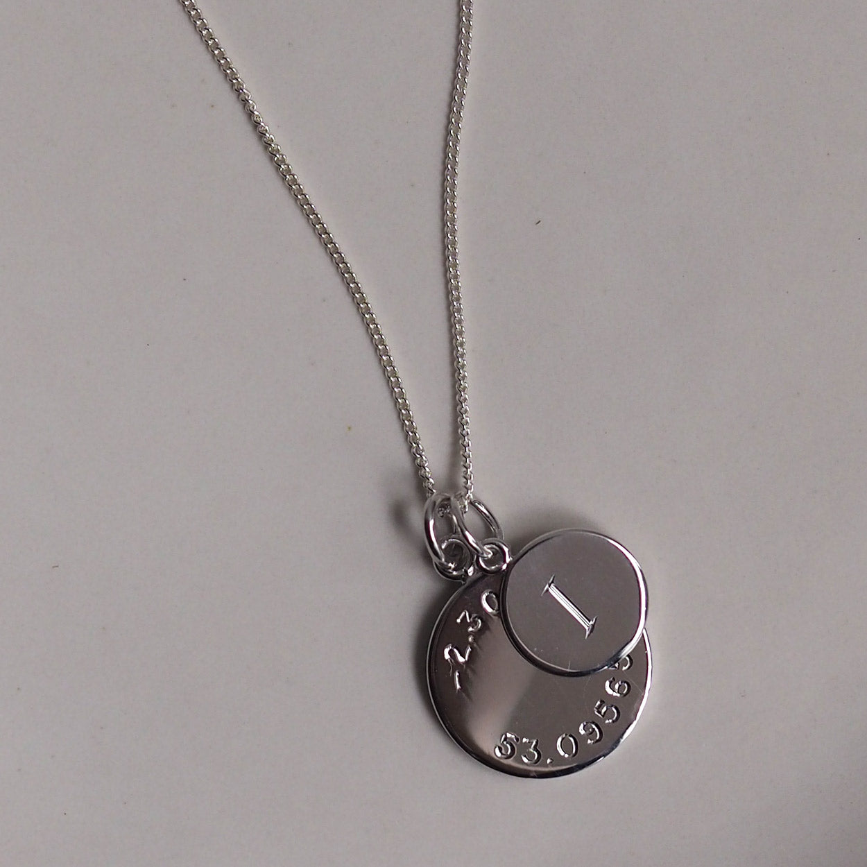 Personalised Latitude &amp; Longitude Mini Initial Necklace in Solid Silver with hand-engraved coordinates and initial. A meaningful keepsake of cherished memories.