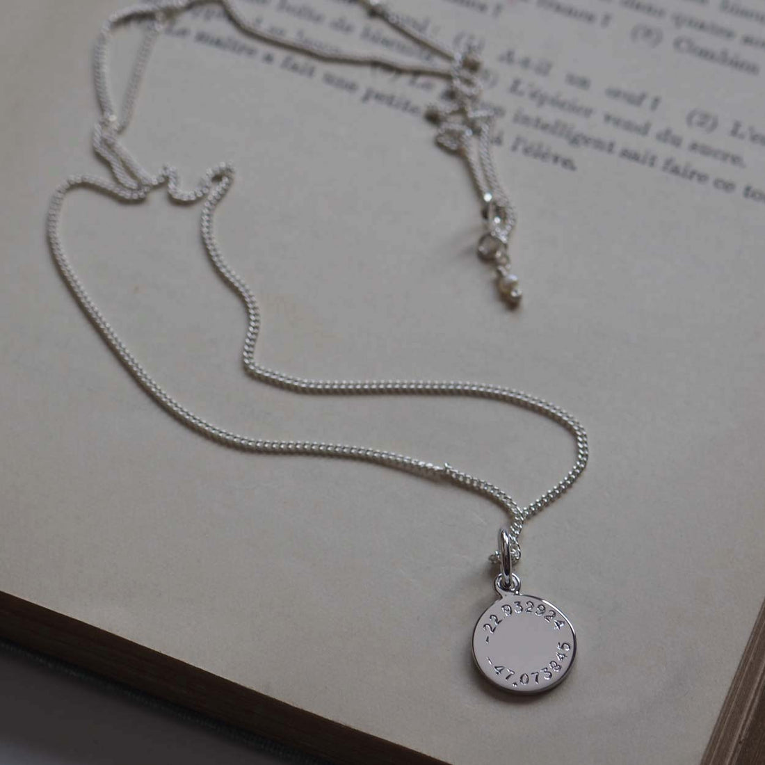 Latitude and Longitude Mini Necklace charm in solid 9ct gold, hand-engraved with coordinates. A timeless keepsake symbolizing cherished memories.