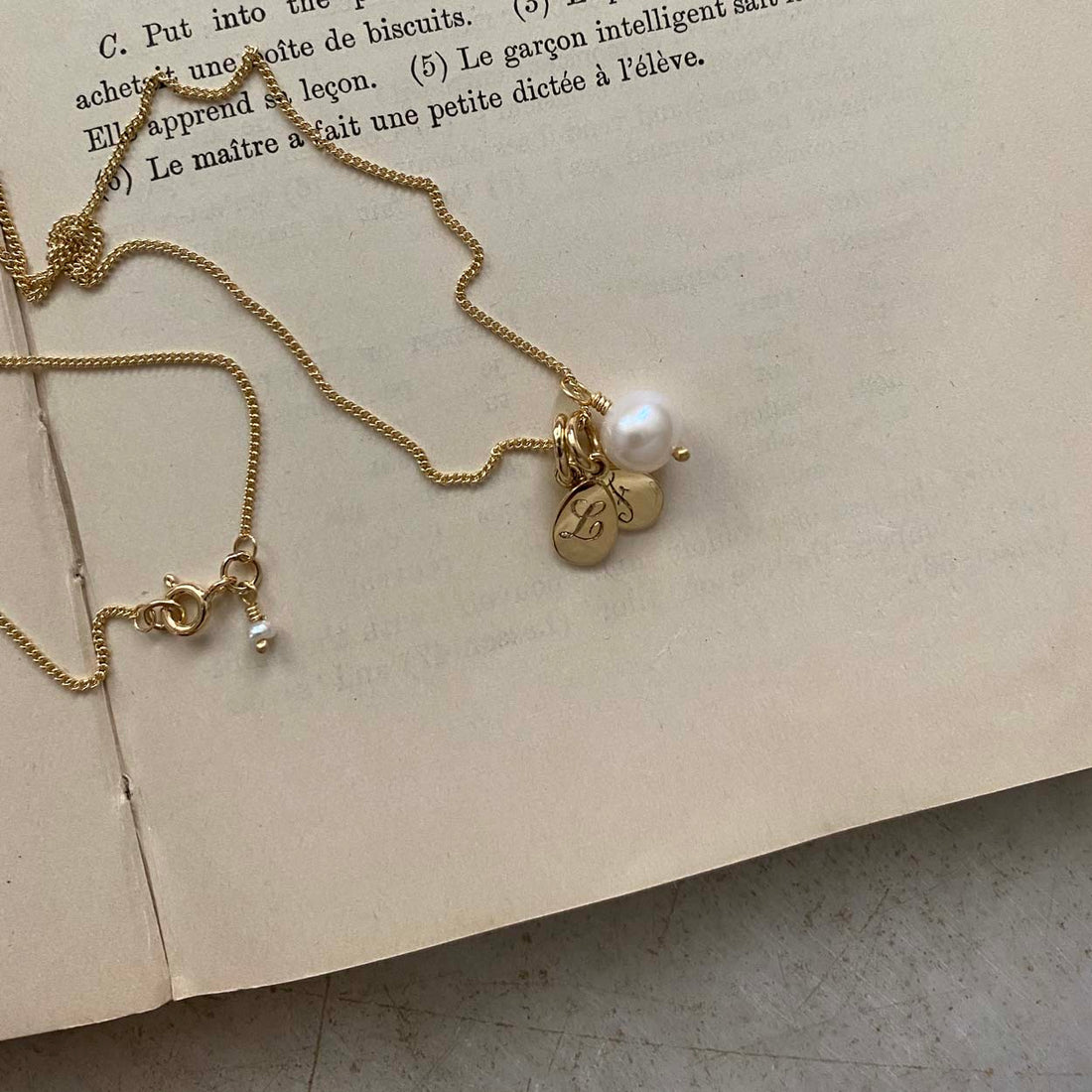 Double Teardrop Initial and Pearl Necklace in Solid Gold with two engraved teardrop pendants and a pearl charm. A timeless piece symbolizing love and cherished connections.