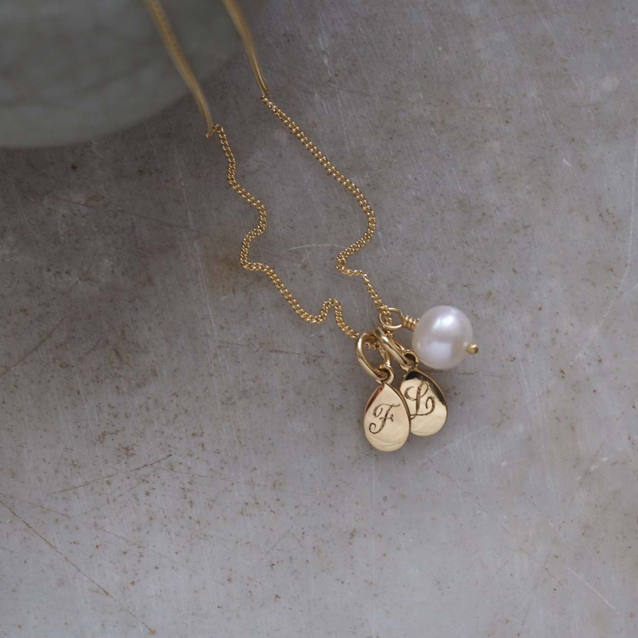 Double Teardrop Initial and Pearl Necklace in Solid Gold with two engraved teardrop pendants and a pearl charm. A timeless piece symbolizing love and cherished connections.