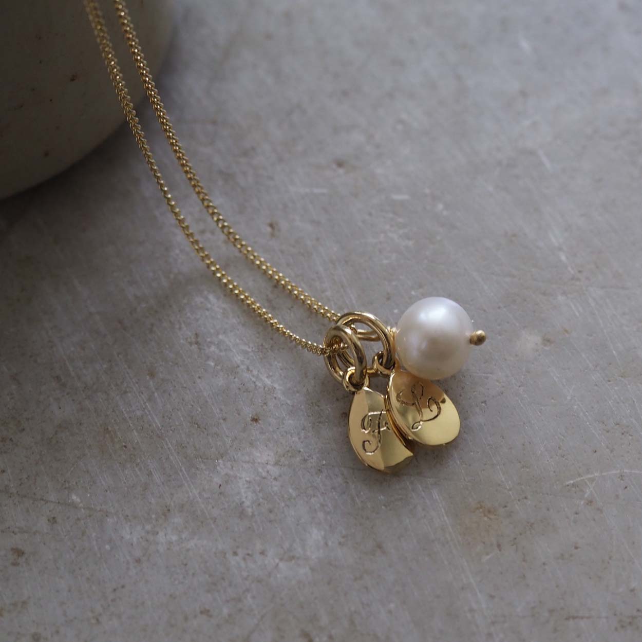 Double Teardrop Initial and Pearl Necklace in Solid Gold with two engraved teardrop pendants and a pearl charm. A timeless piece symbolizing love and cherished connections.