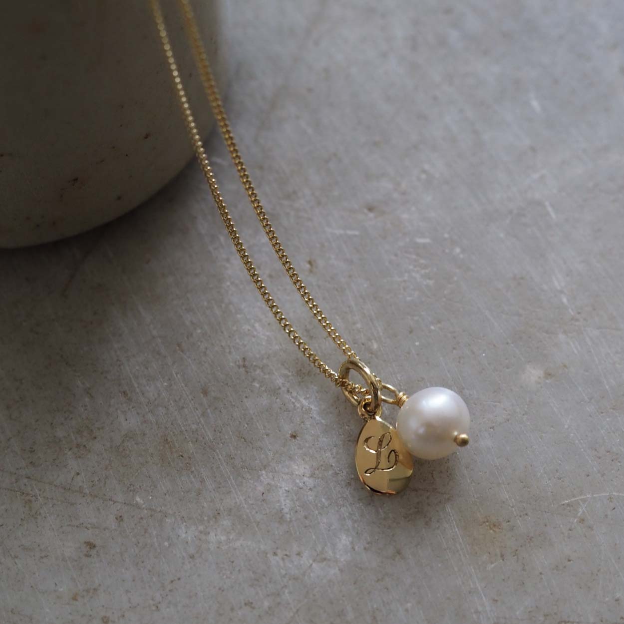 Teardrop Initial and Pearl Necklace in Solid Gold with an engraved teardrop pendant and a pearl charm. A timeless piece symbolising love and cherished connections.