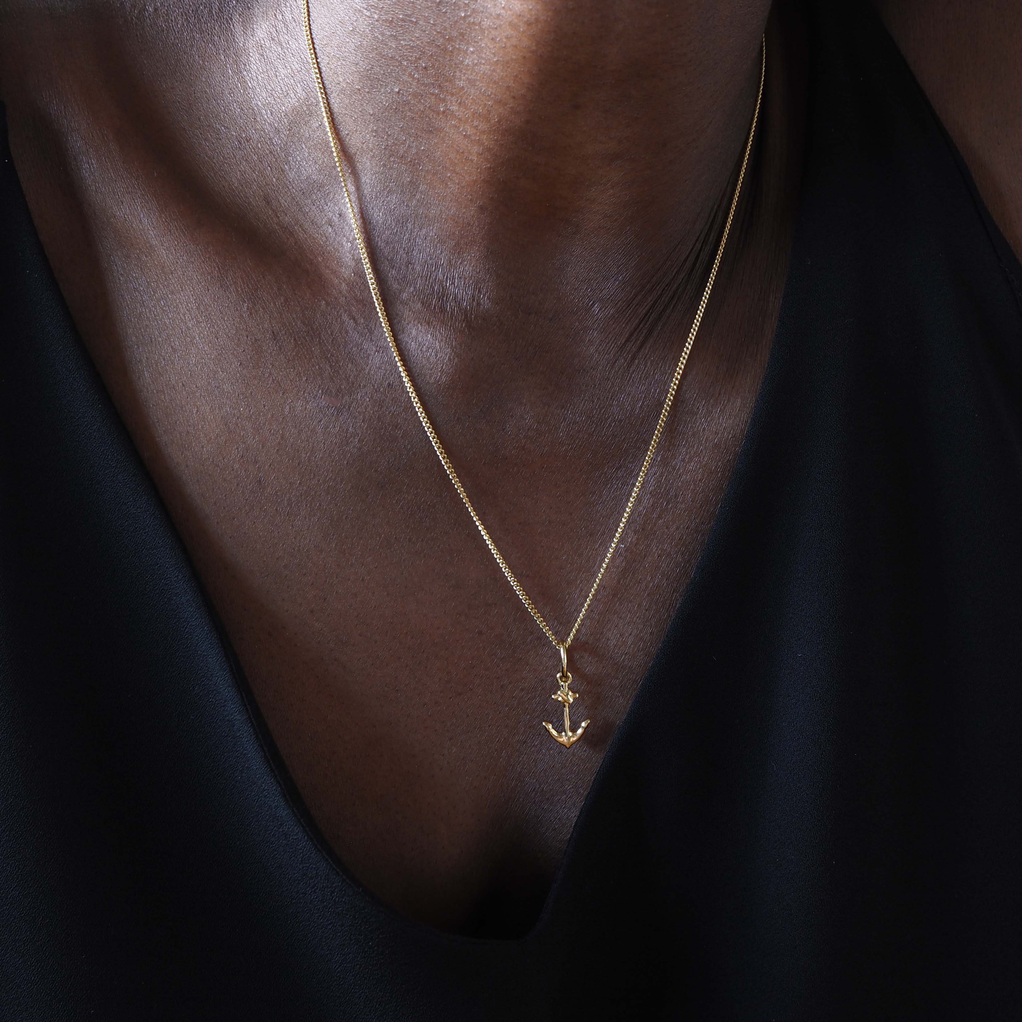 Gold anchor necklace close-up on model’s neck and collarbone