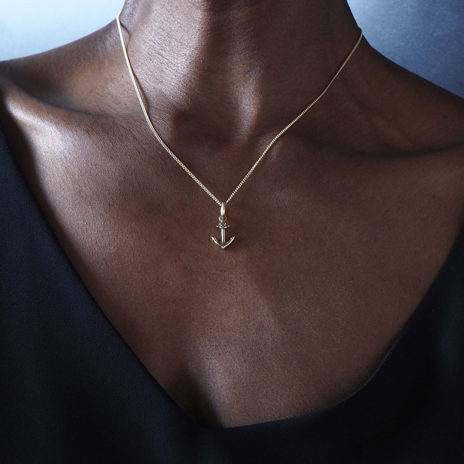 18ct gold anchor pendant necklace styled with a black vest
