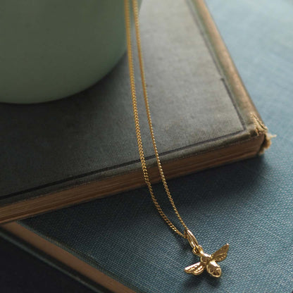 18ct gold bee necklace on fine chain, flatlay jewellery photo - close up