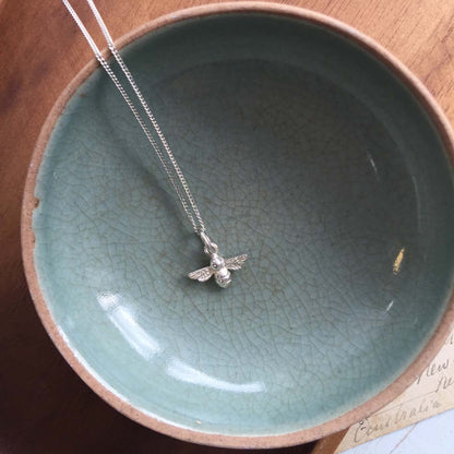 Sterling silver bee charm necklace on chain, flatlay jewellery photo