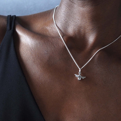 Close up of sterling silver bee necklace pendant one model wearing black vest