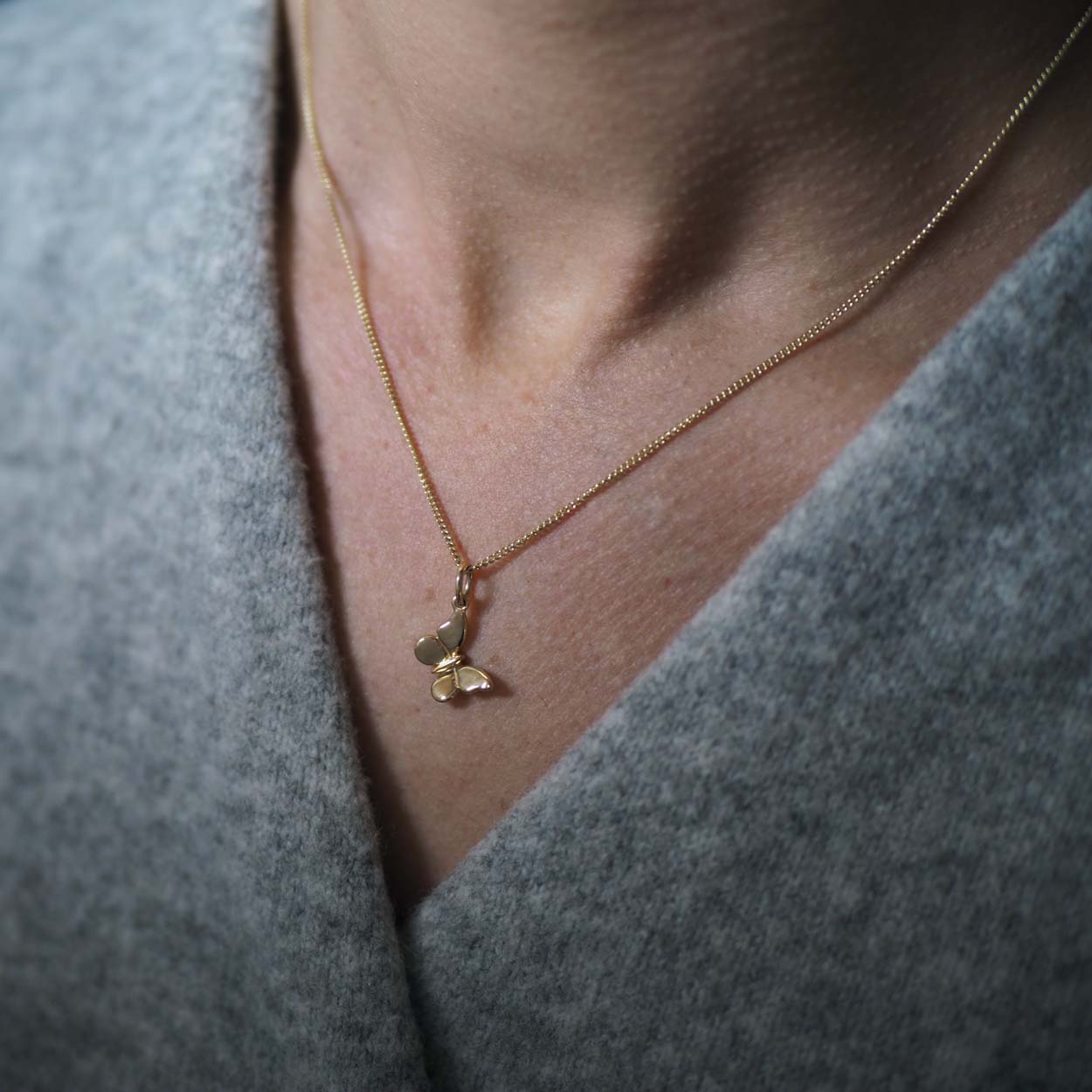 Woman wearing the Butterfly Necklace in solid yellow gold, a modern talisman of change and new beginnings