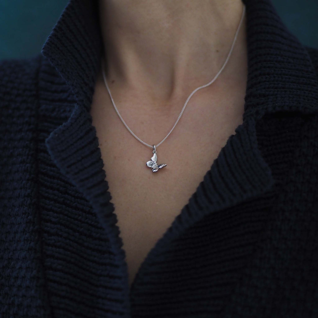 Woman wearing the Butterfly Necklace in solid gold, a modern talisman of change and new beginnings.