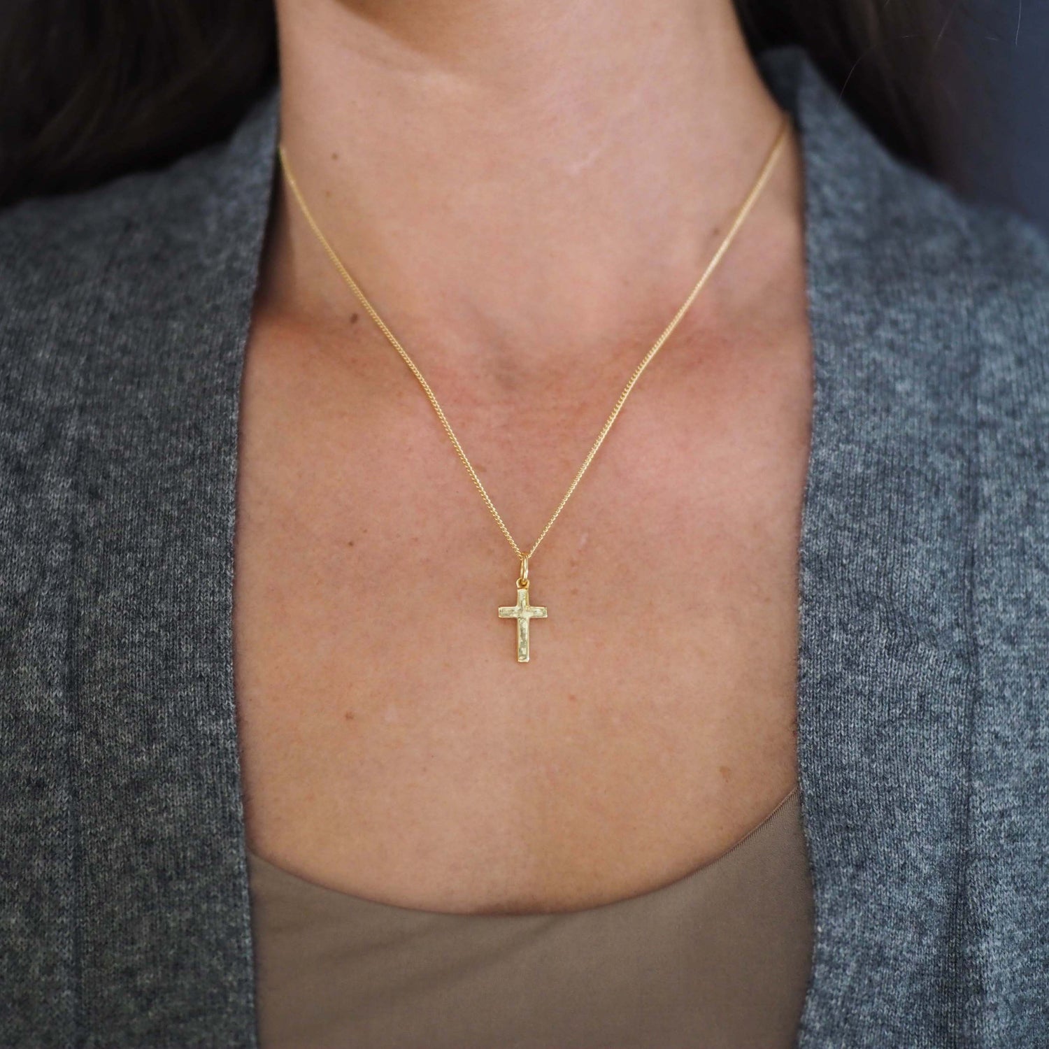 Woman wearing the Solid Gold Cross Necklace, showing soft proportions and detailed hand-texture