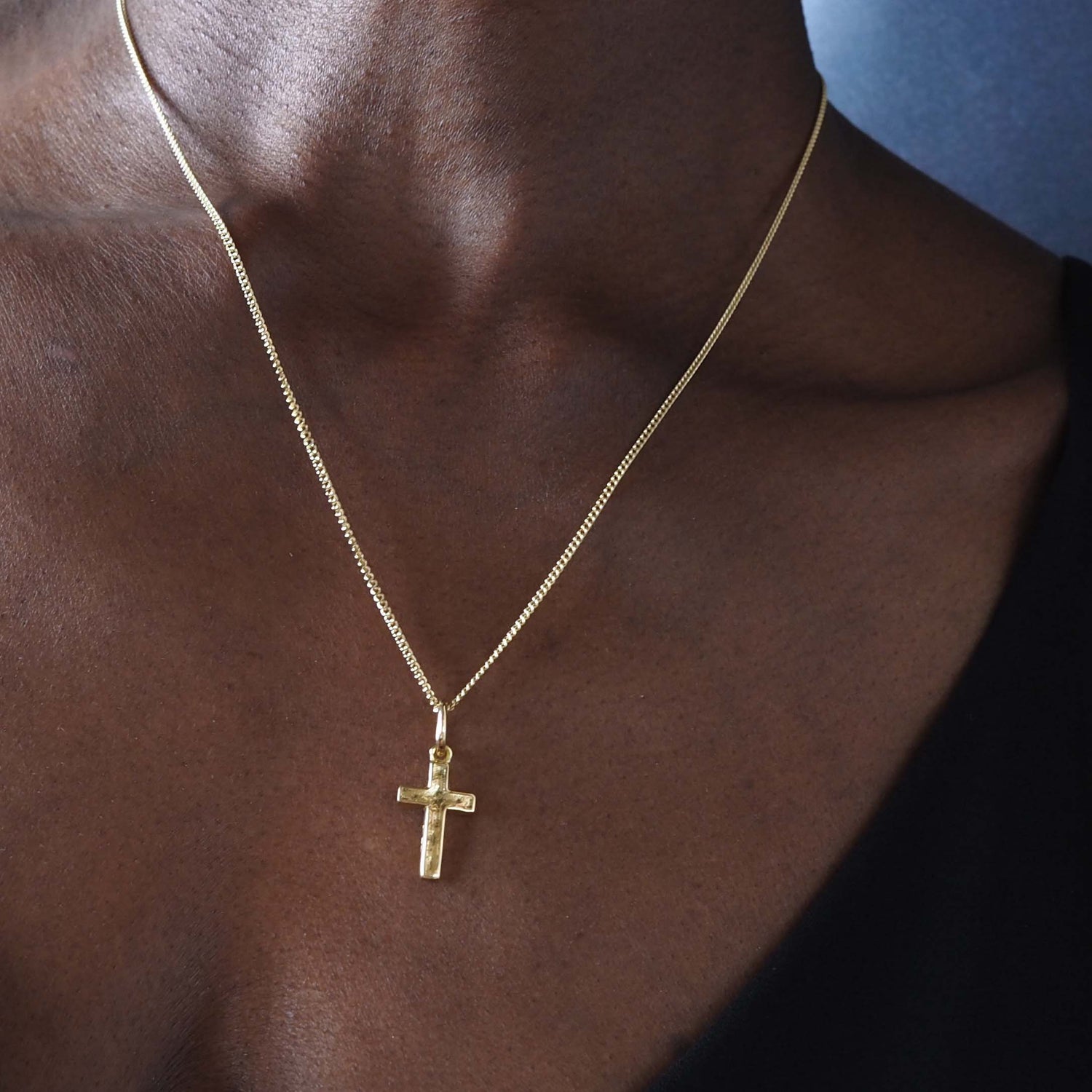 Woman wearing the Solid Gold Cross Necklace with handcrafted texture and sculptural design