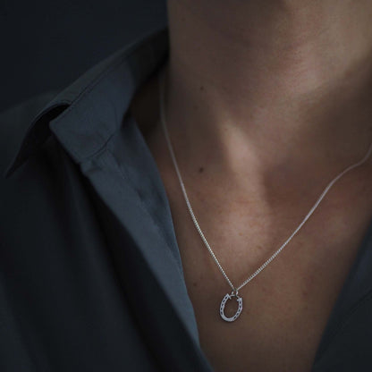 Woman wearing the Horseshoe Necklace in solid gold, a talisman of luck and protection