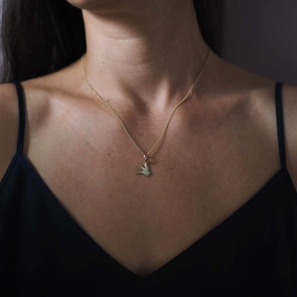 Solid gold swallow necklace on model – handcrafted talisman symbolising hope, love, and safe return