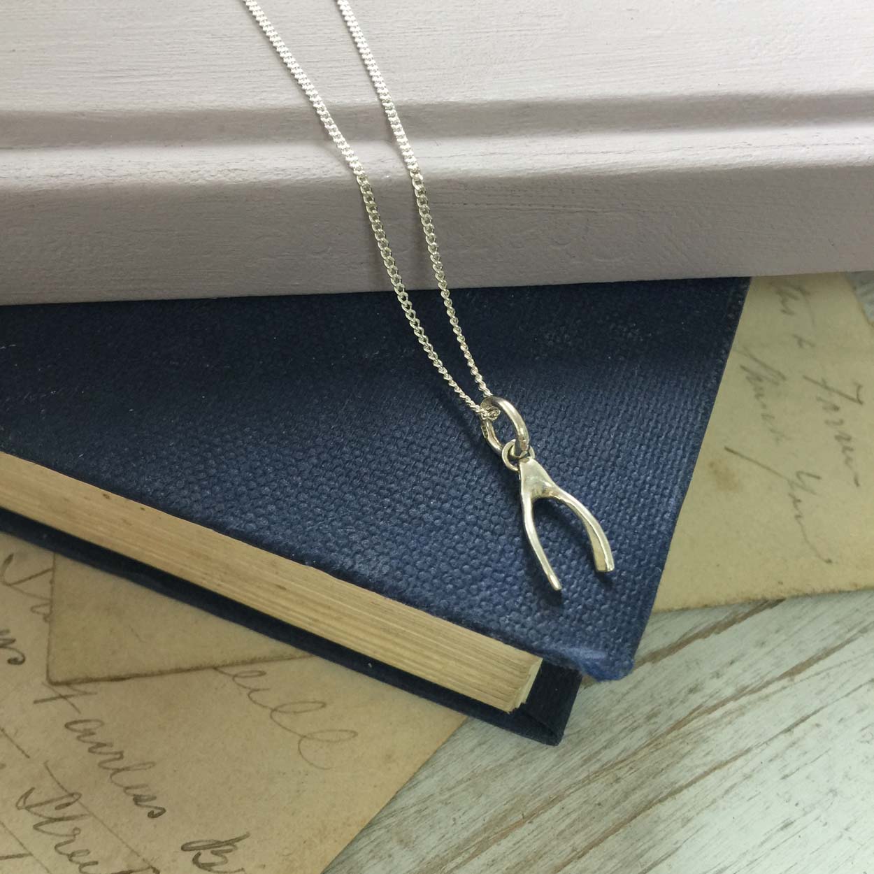 Gold wishbone charm necklace symbolising luck and hope