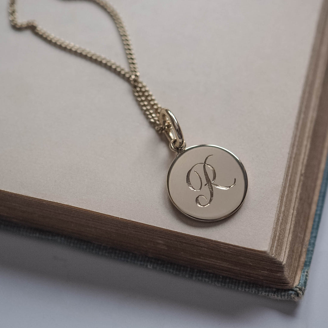 Initial Mini Necklace in Solid Gold with a hand-engraved scrolled initial, available in yellow, rose, or white gold. A delicate piece for personal storytelling and meaningful gifting.