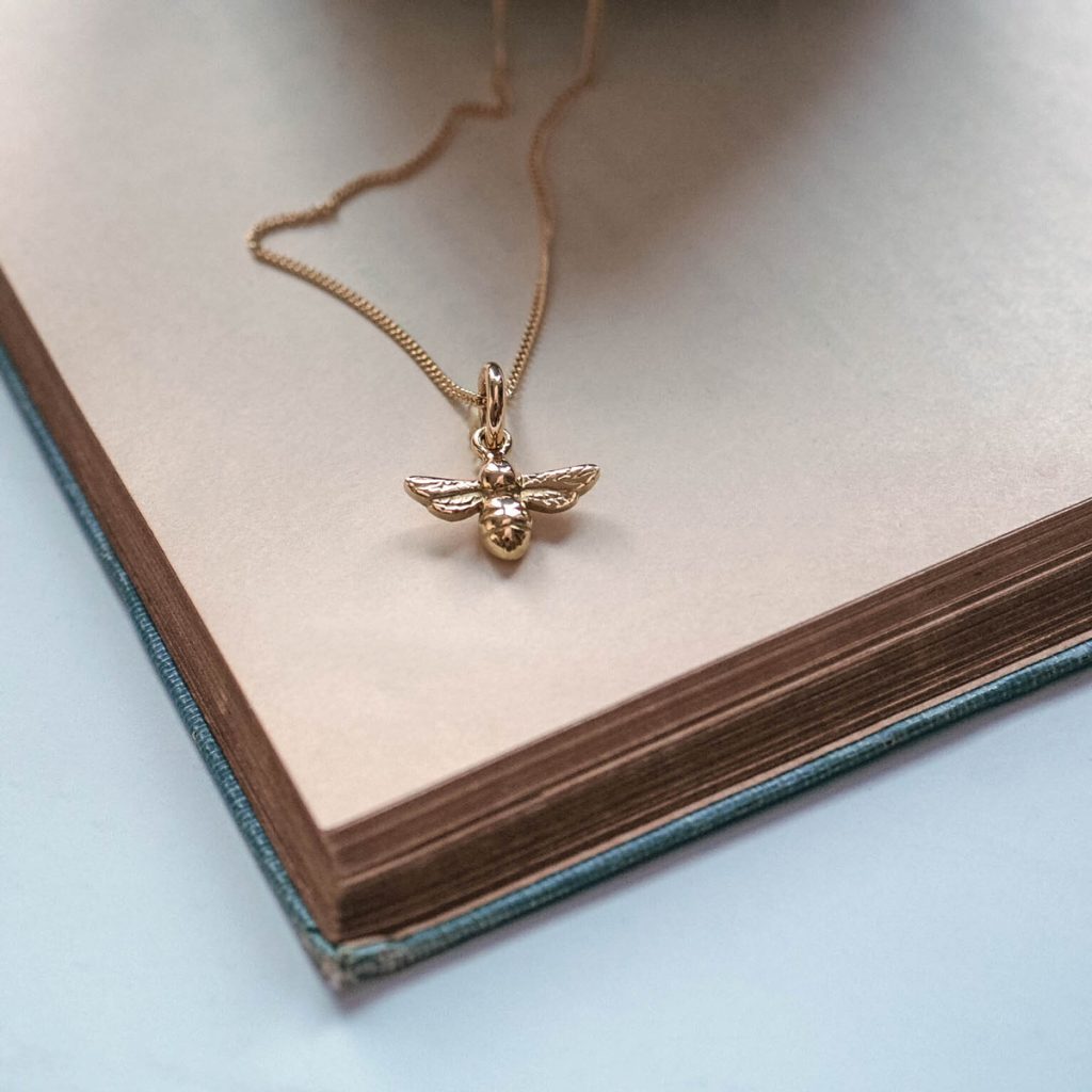 18ct gold bee necklace on fine chain, flatlay jewellery photo