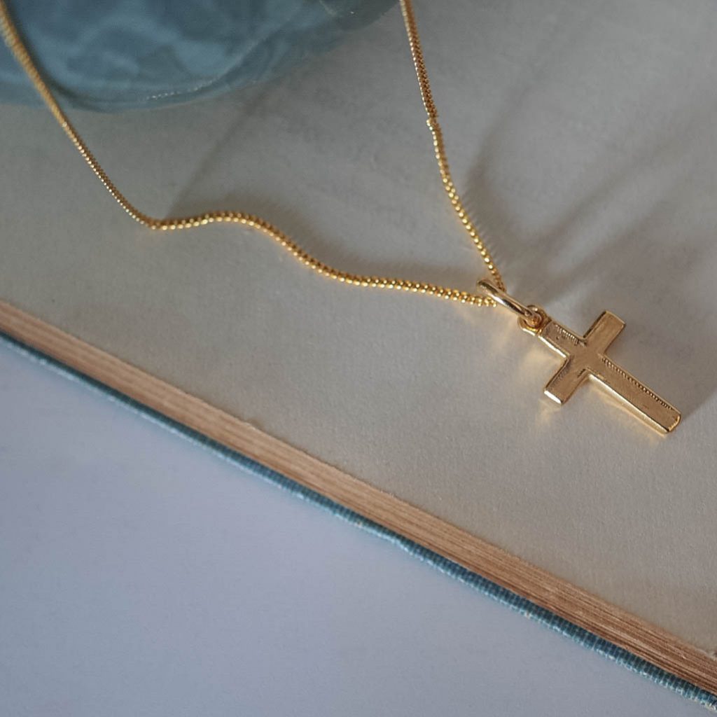 Refined solid gold cross pendant showing soft proportions and detailed hand-texture