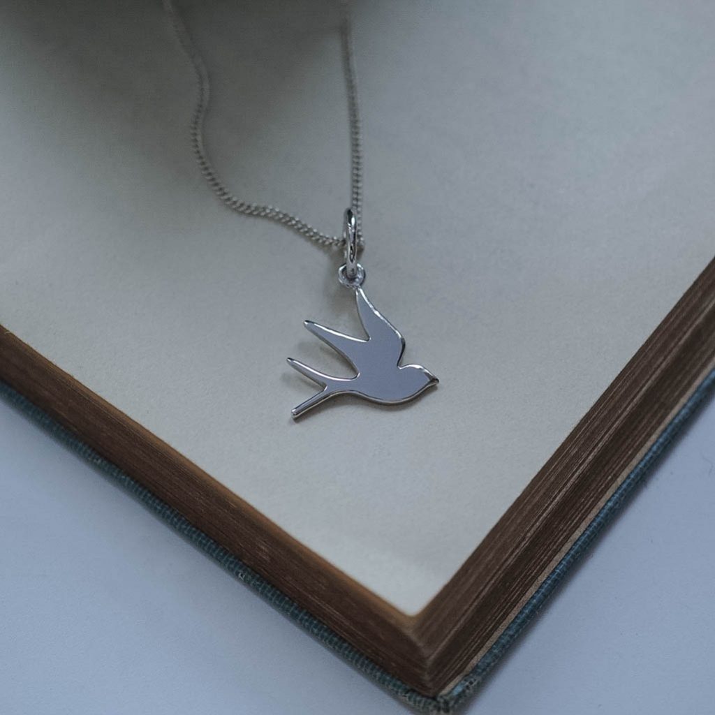 Handmade swallow charm in solid gold, high polish finish symbolising homecoming and resilience