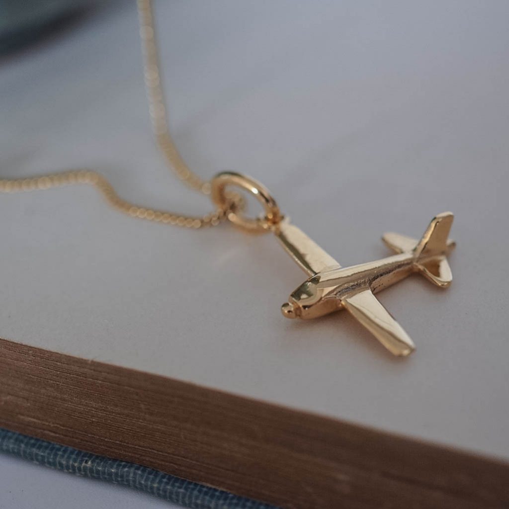 Close-up of 9ct gold airplane pendant showing polished finish